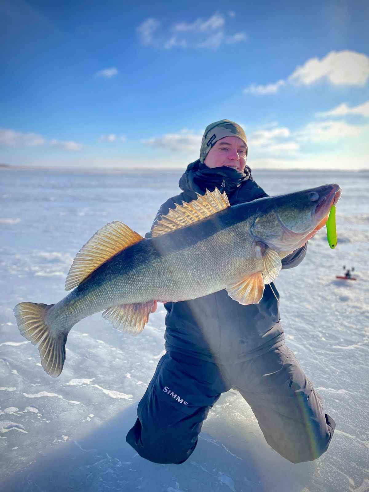 Фотограф IceClub снимает участников с их уловом на зимней рыбалке.