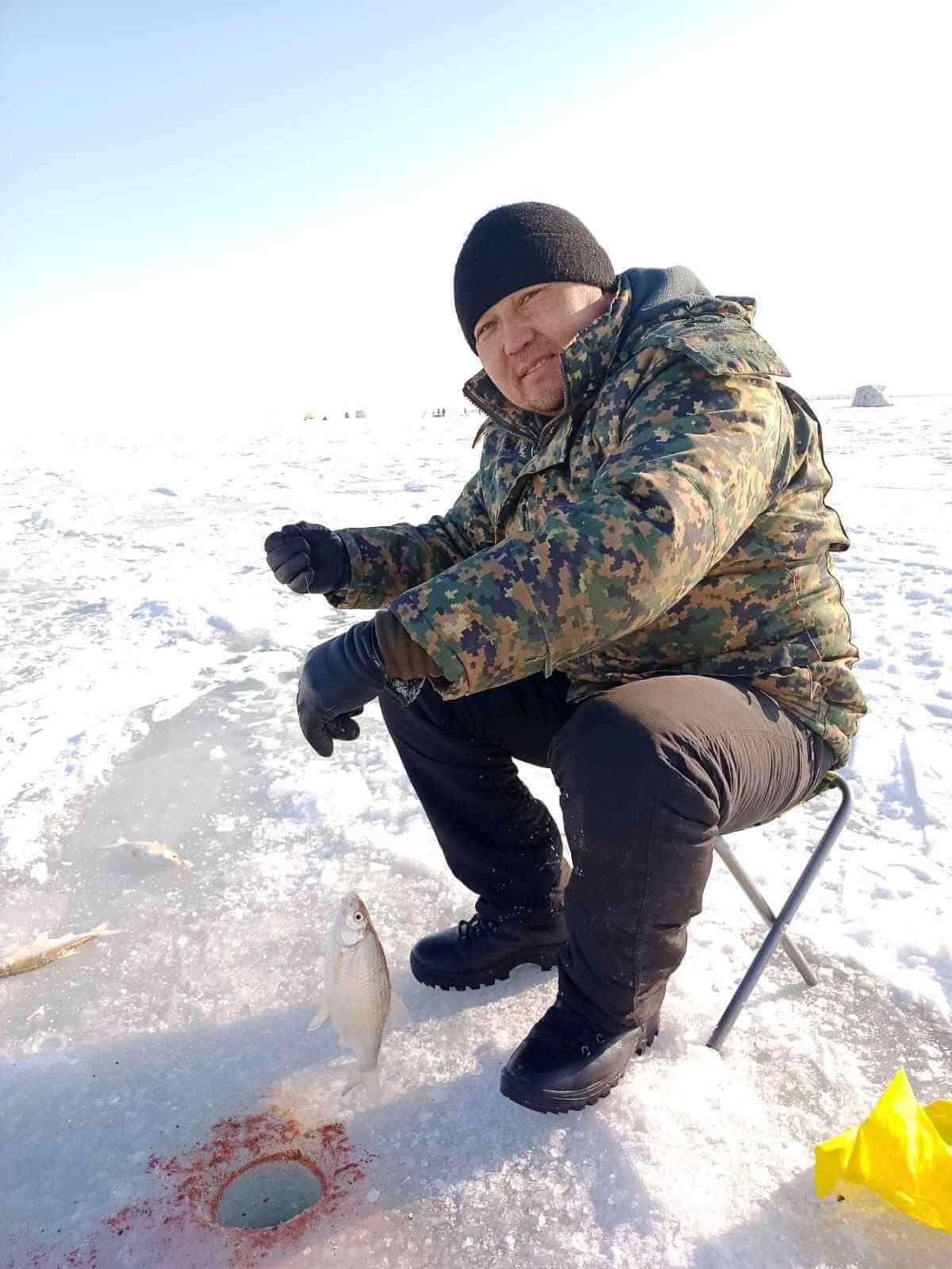 Участник IceClub показывает трофейную рыбу после ice fishing.