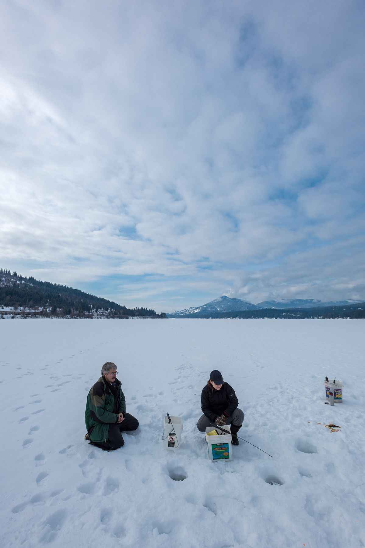Группа рыболовов IceClub на зимнем выезде с палатками и снаряжением на льду.